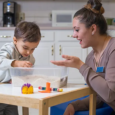 A U N E occupational therapy student works with a child at a sensory table