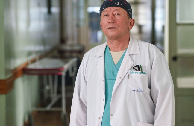 A photo of a surgeon posing in a hospital hallway