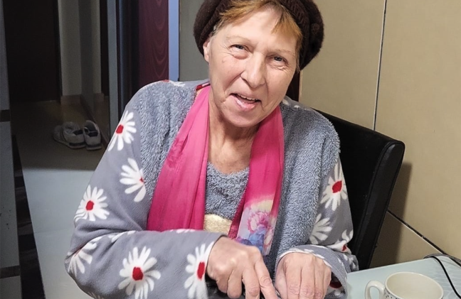 A woman from Romania smiles in her kitchen