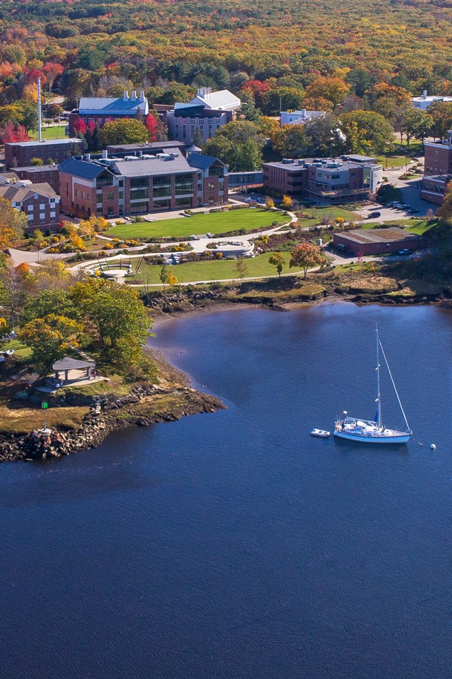 Aerial view of brick buildings surrounded by trees and next to a river