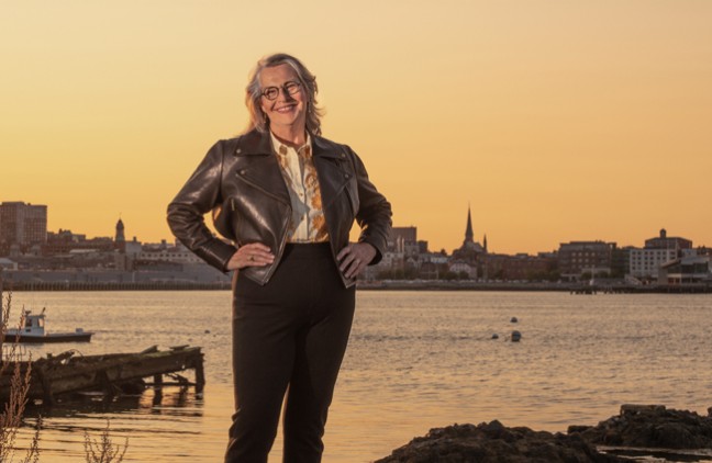 Karen Houseknecht standing infront of Casco Bay and the city of Portland