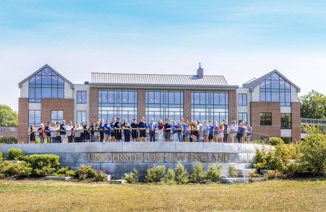 College of Business students and faculty stand in front of the UNE Commons on the Biddeford Campus