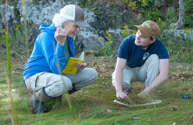 Pam Morgan and Robyn Rollo crouch down to survey a section of the marsh for invertibretes 