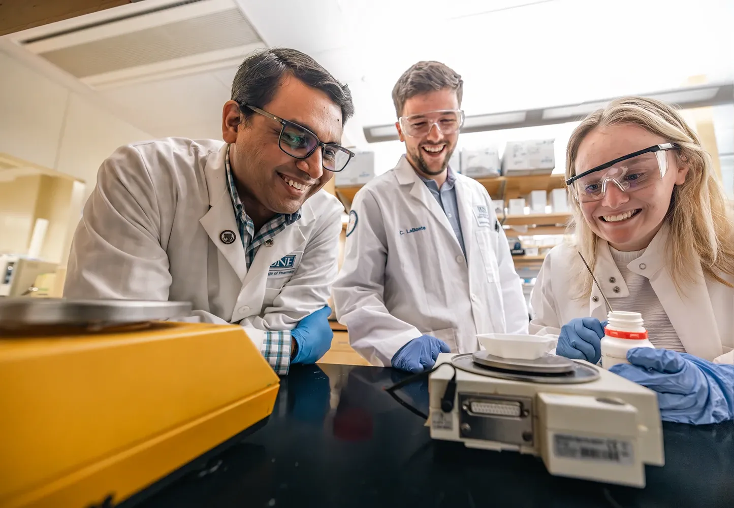 U N E faculty member and researchers Sri Mohan on the left stands next to two students working together in Mohan's lab