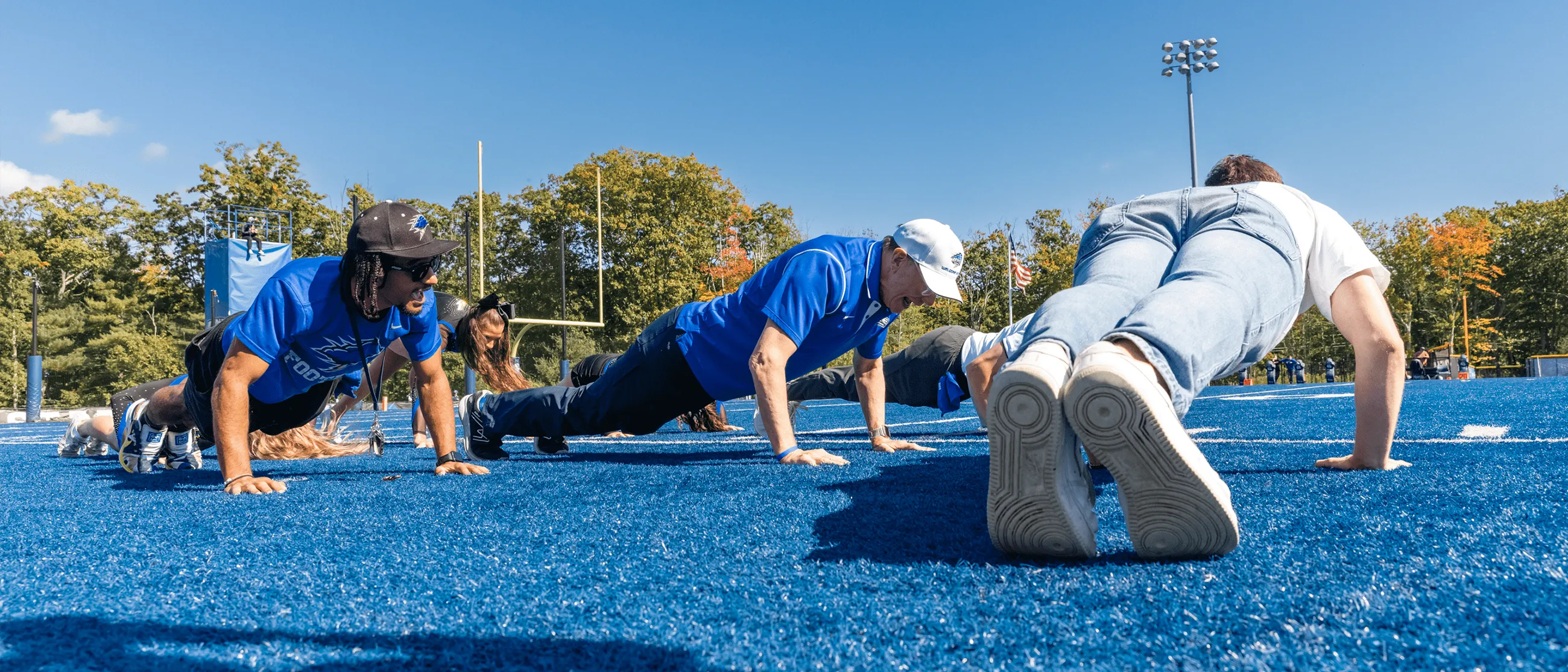 UNE President James Herbert does pushups on the sidelines of UNE's football field at Homecoming