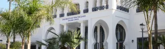 The exterior of main building on U N E's Tangier, Morocco campus surrounded by palm trees