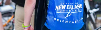 a student wears a u n e backpack 