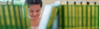 A student is visible behind a row of books