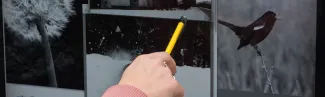 a hand holds a pencil and points to a computer screen using software design zephyr