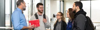 Four undergraduate students speak with a faculty member