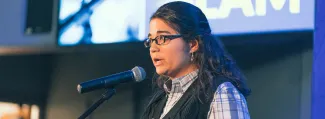 woman on stage speaking into mic