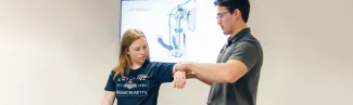 A P T student practices arm exercises on another student