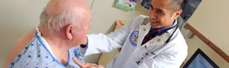 A C O M student speaks with a geriatric patient in a doctor's office