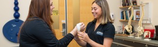 An athletic training student practices wrapping the wrist of another student