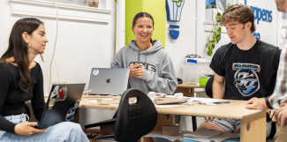 Three UNE students work around a table in the Makerspace