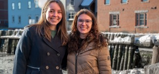 Two women pose in front of the Portland waterfront