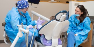 UNE dental students engage with a child patient in the Oral Health Center