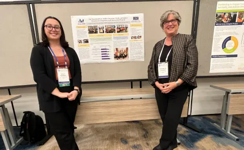 Photo of Emily Thomas and Kathryn Loukas posing in front of a research poster