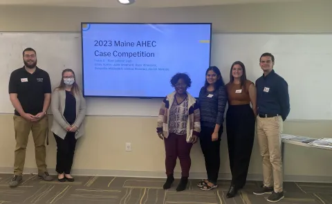 Six students pose against a projector screen in Innovation Hall