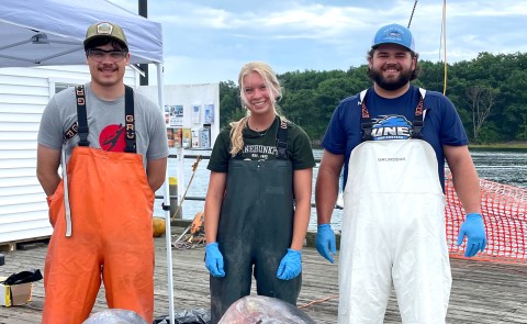 Three marine science students pose on the pier at Camp Ellis along the Saco River