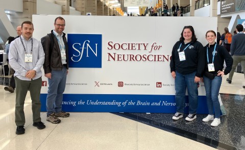 A group of UNE researchers pose in front the Society for Neuroscience sign