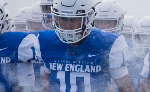 UNE football team members walk through the fog