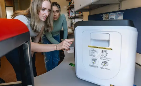 Two students operate a 3D printer