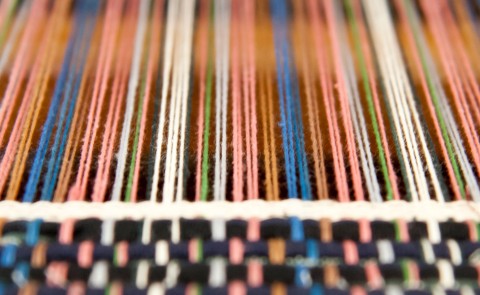 Spools of thread are shown along a loom 