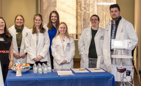 Pharmacy students pose with a UNE alum at a blood pressure clinic