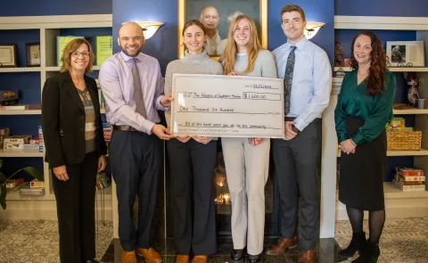 UNE medical students and local health leaders pose holding a large check in the amount of $1,600