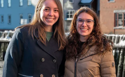 Two women pose in front of the Portland waterfront