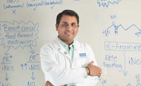 Portrait of Sri Mohan against a whiteboard with chemical formulas