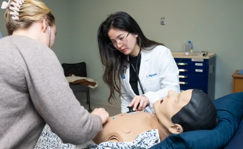 A medical student and PA student listen to the heartbeat of a high-fidelity patient simulation mannequin