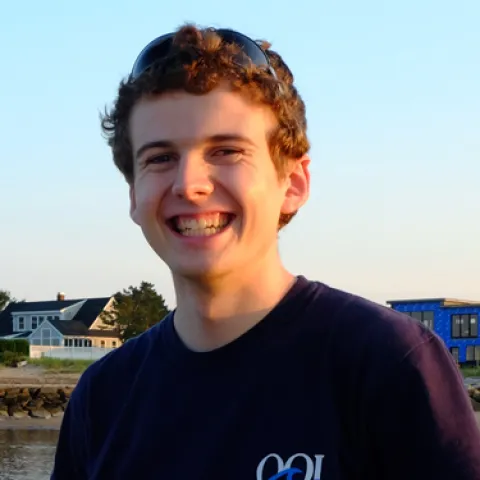 Andy Robinson stands on a beach smiling at the camera