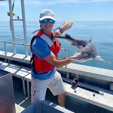 U N E student Clayton Sure hold a fish he caught on a boat