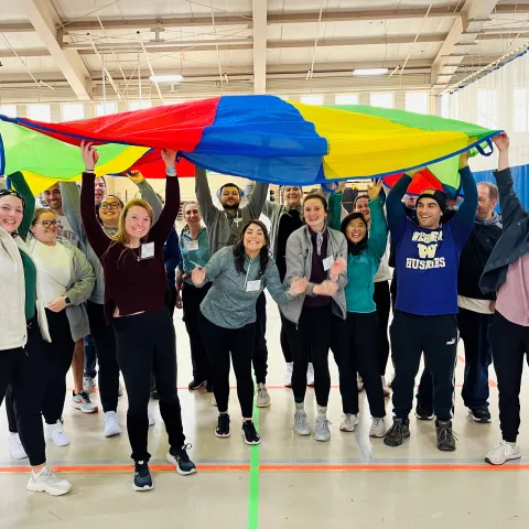 students holding up colorful parachute