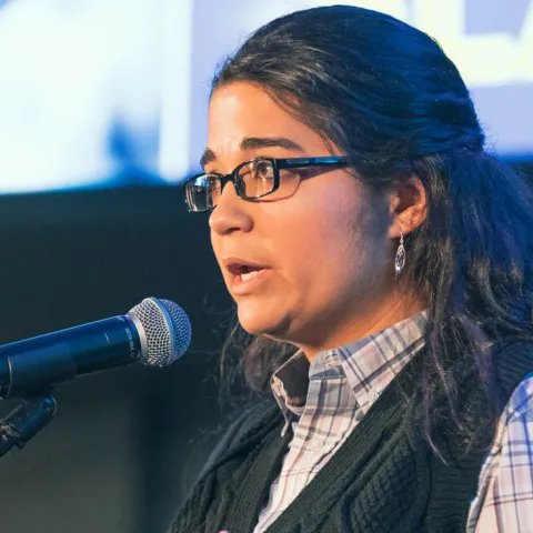 woman on stage speaking into mic