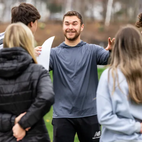 A UNE student gives game instructions to a group of high schoolers