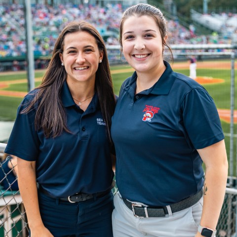 Two UNE business students pose in front of the baseball diamond at Portland's Hadlock Field