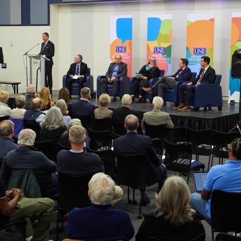 UNE President James Herbert introduces four panelists and a moderator onstage