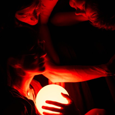 Two dancers stare into a red, glowing orb