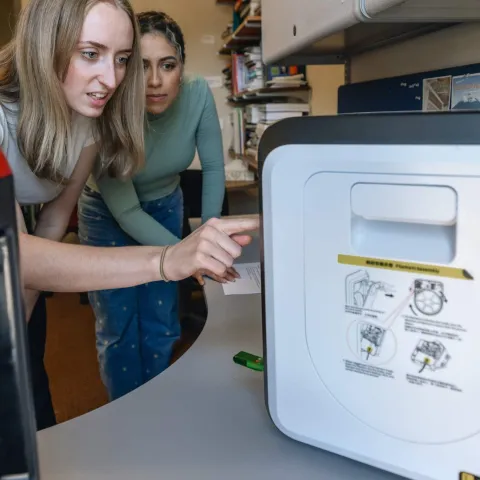 Two students operate a 3D printer