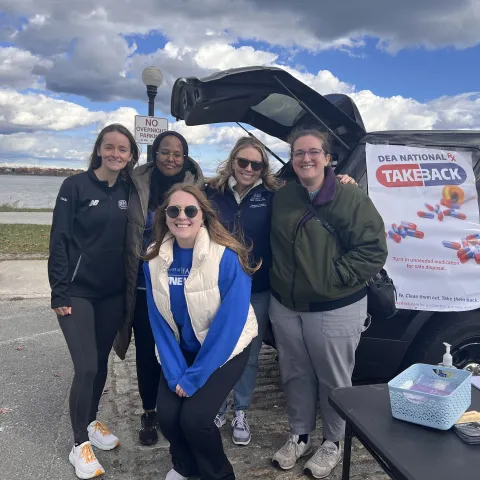 UNE Pharmacy students and faculty pose for a photo by the water at Drug Take Back Day