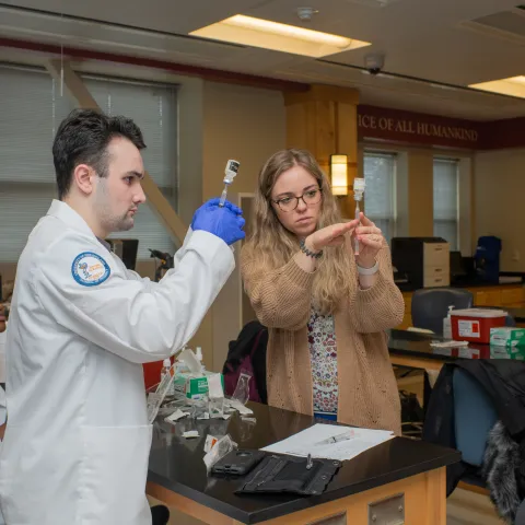 UNE pharmacy students draw vaccines from vials in a lab setting