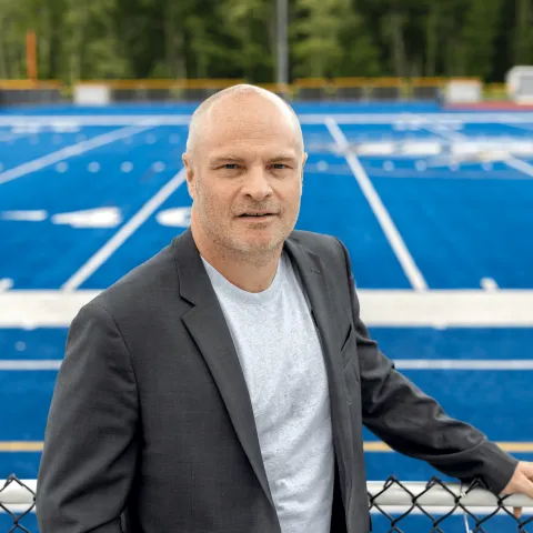 Portrait of Norm O'Reilly with the UNE football field in the background