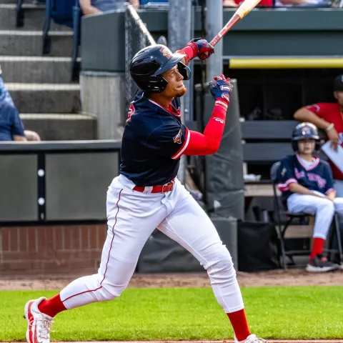 A baseball player follows through with a swing at Hadlock Field in Portland