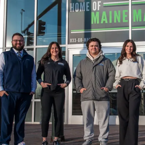 UNE business students pose in front of the Cross Insurance Arena in Portland