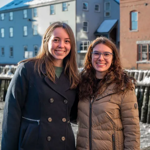 Two women pose in front of the Portland waterfront