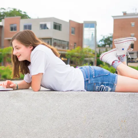 A UNE student works on her laptop outside the Danielle N. Ripich Commons